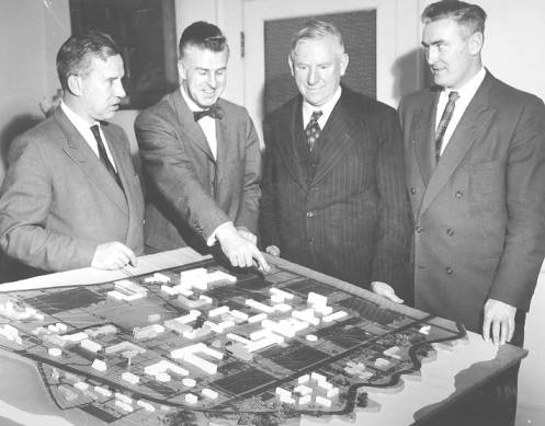 Roy Jessiman points out interesting features of relief map showing future development at UBC, 1958. Left to right: Geoffrey Andrew, Roy Jessiman, Norman Mackenzie, T.S. Hughes. Photo credit: UBC Archives.